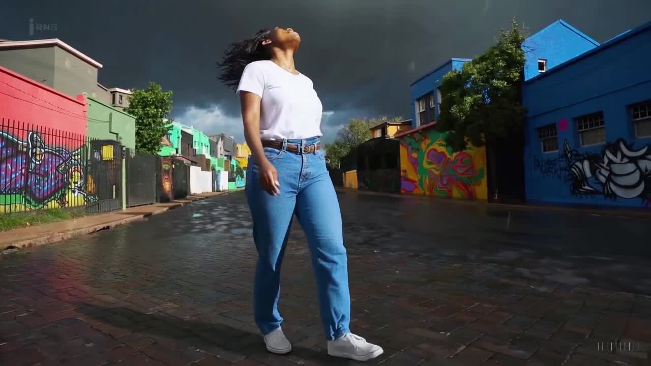 一个穿着蓝色牛仔裤和白色T恤的女人在南非约翰内斯堡冬天的风暴中愉快地散步。